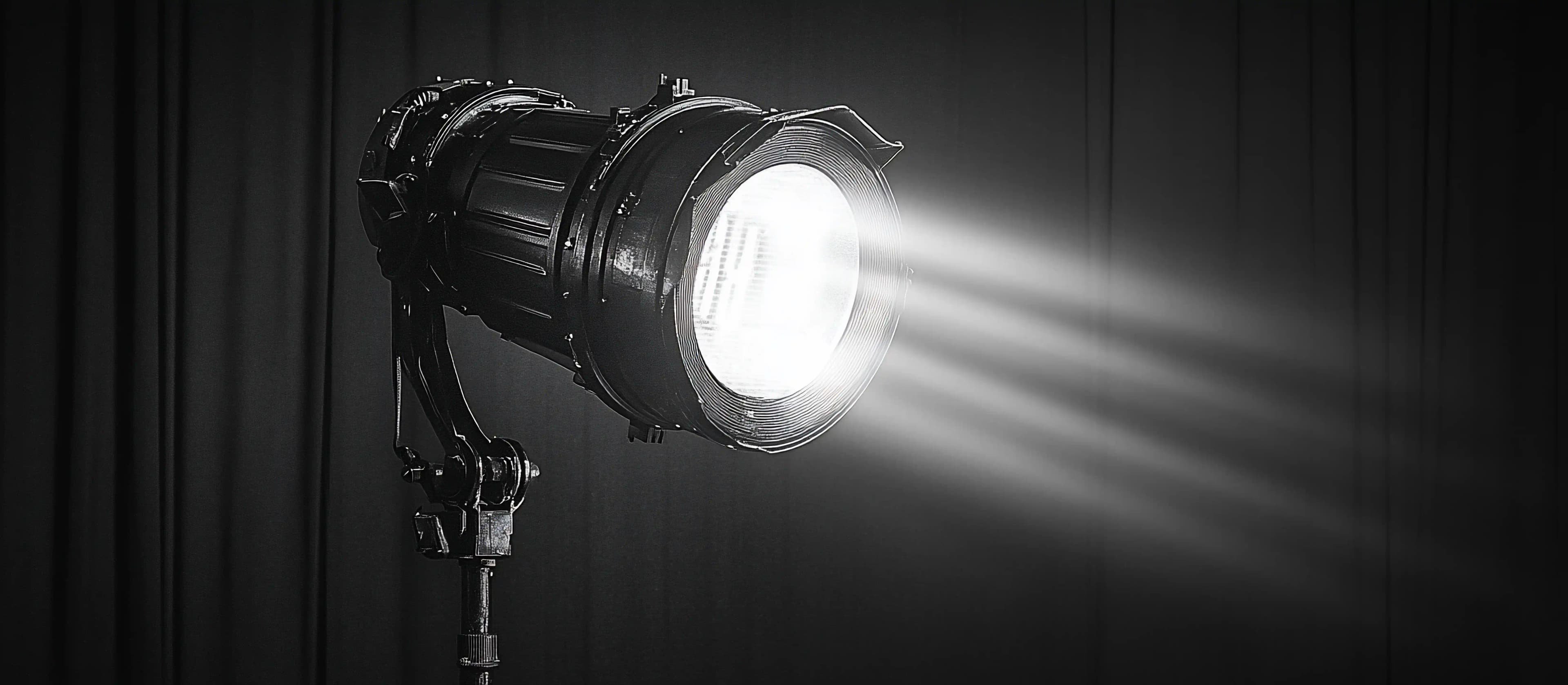 Dramatic spotlight on white-cloth restaurant table set for two with tall wine glasses in darkness, at the table dining experiences and culinary culture