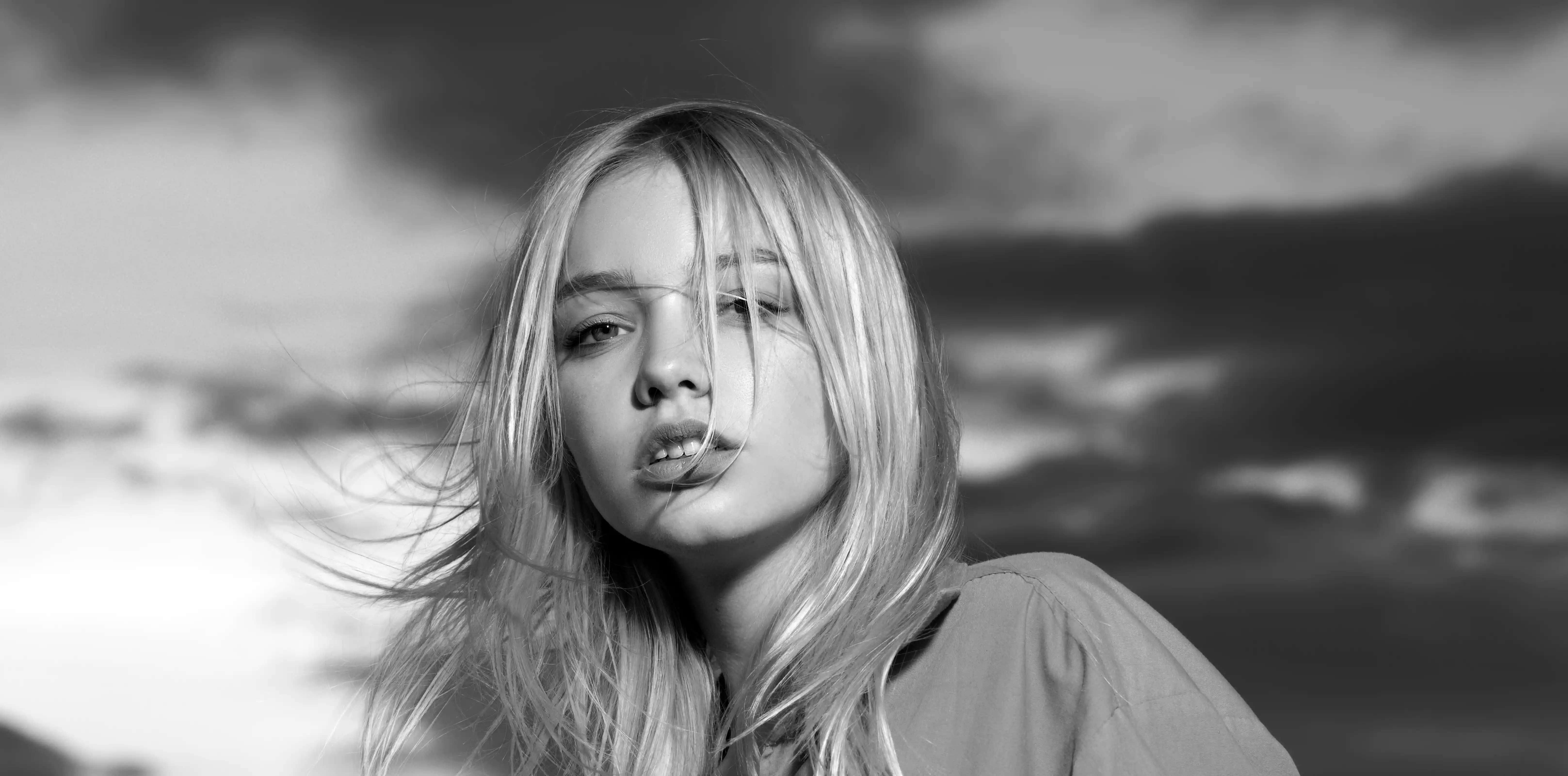 Close-up portrait of woman in dramatic wide-brim spiral hat gazing upward against dark background, modern aesthetics contemporary design visual style and fashion editorial